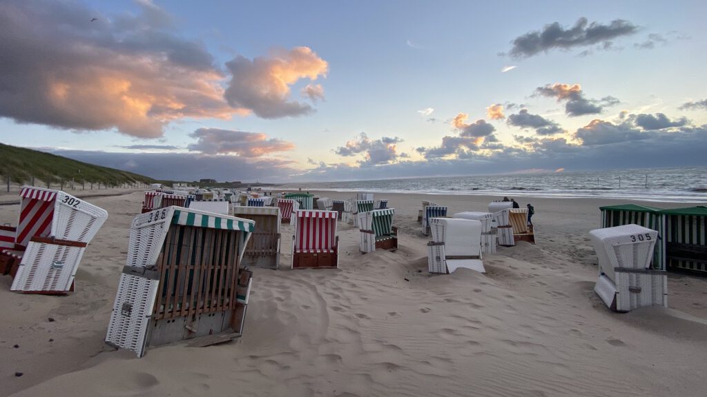 Strandkörbe am Strand mit Aussicht auf die Nordsee im Dämmerlicht und Wolkenhimmel