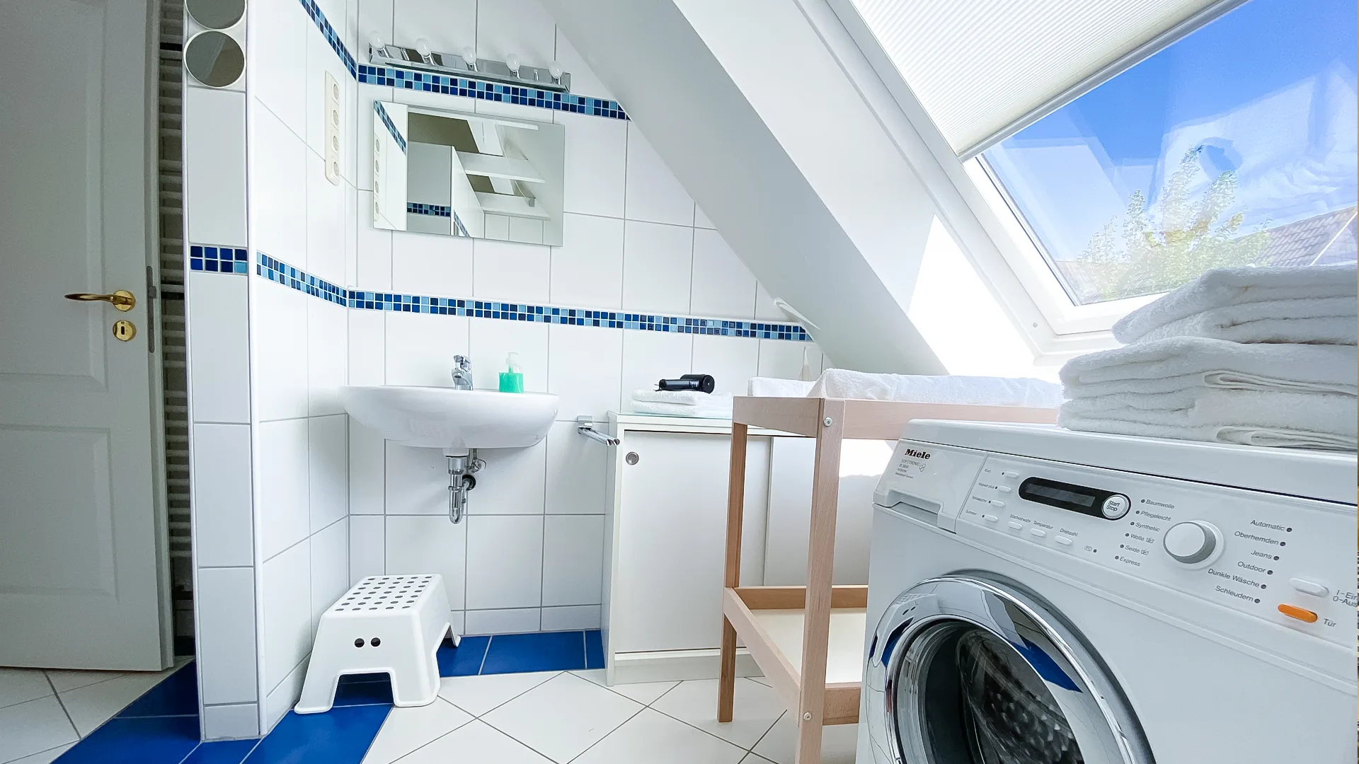 Großes, lichtdurchflutetes Badezimmer mit Waschbecken, Spiegel, Wickeltisch und Waschmaschine im Ferienhaus auf Baltrum