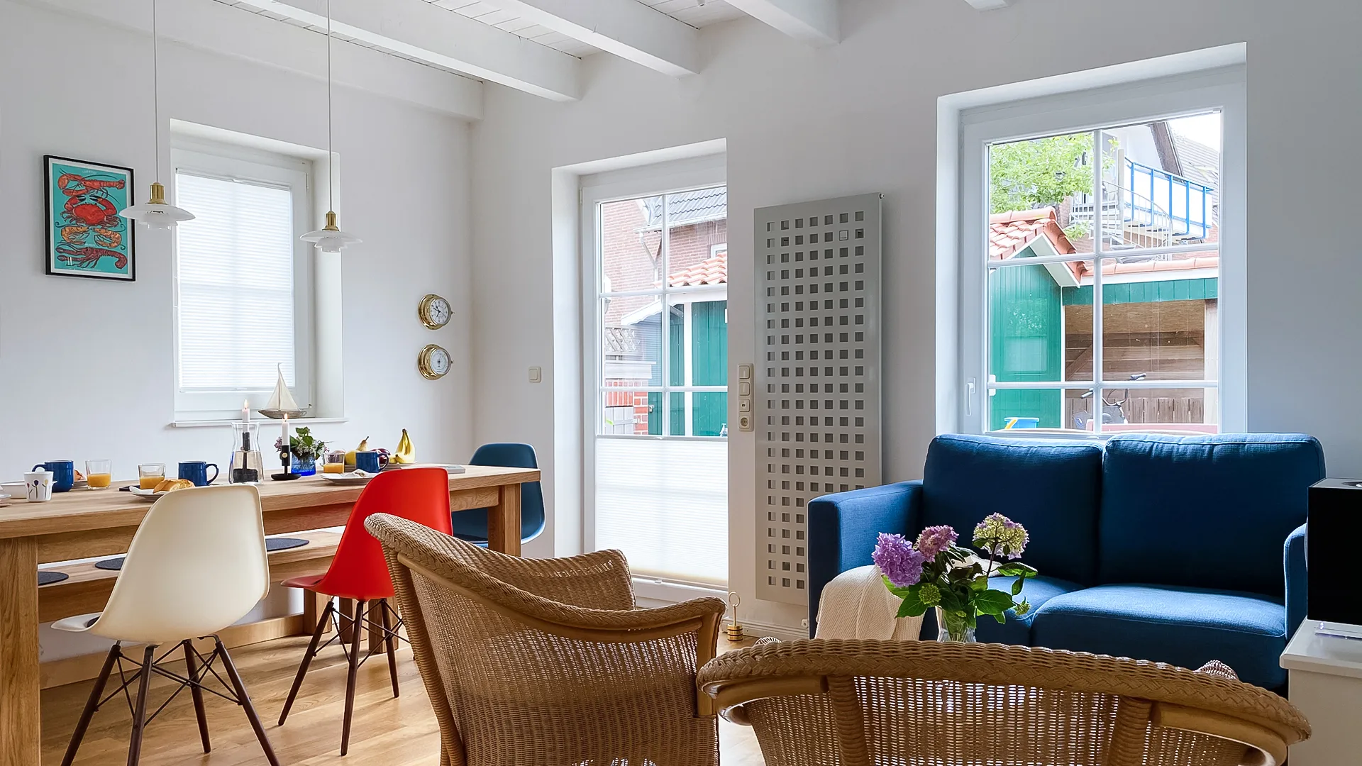 Esszimmer und Wohzimmer mit blauer Couch in einem lichtdurchflutetem Raum, der zum Garten führt.